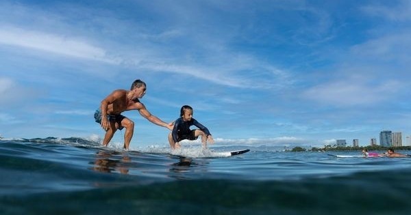 Man helping a boy surf on the ocean